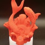 Statue décorative orange du signe astrologique Poissons réalisée en impression 3D, représentant deux carpes entrelacées sur un socle avec le symbole du zodiaque, hauteur 18cm, design moderne et élancé pour décoration intérieure.